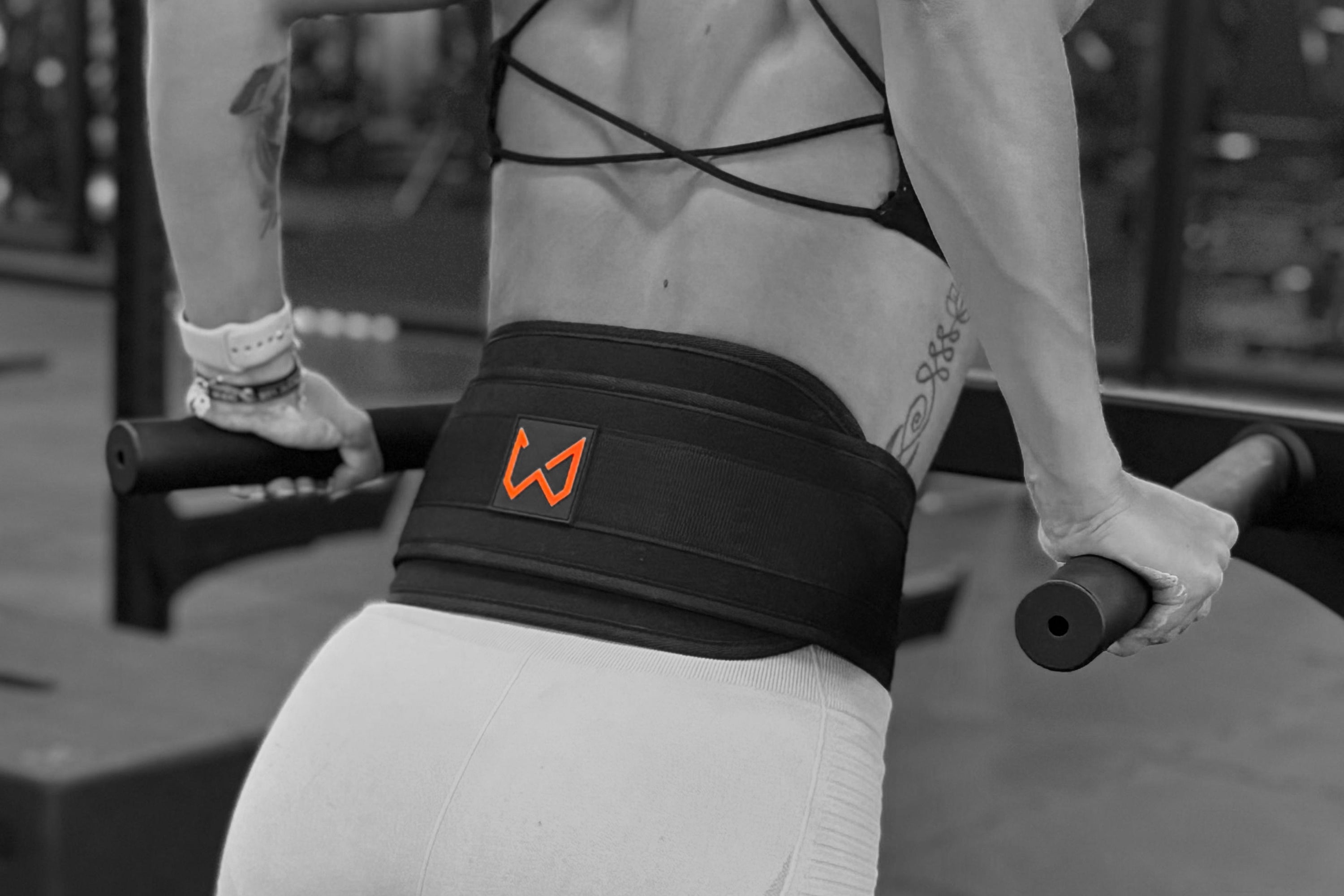 A female athlete using dip belt while doing dips in the gym