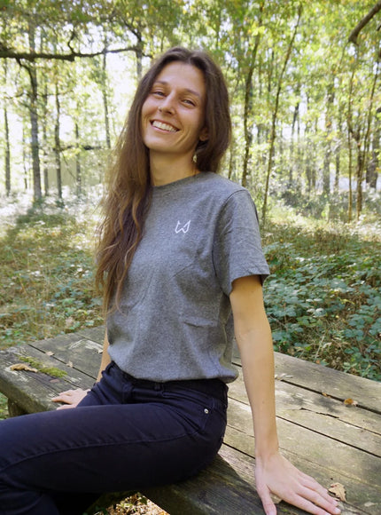 Woman sitting on a wooden bench in a forest wearing hemp and organic cotton tshirt.