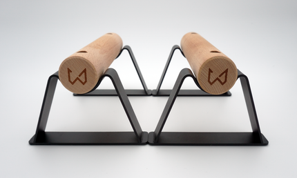 A pair of Antlettes Parallettes with a black powder-coated steel base and wooden handles, designed for calisthenics and bodyweight exercises.