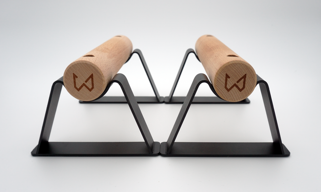 A pair of Antlettes Parallettes with a black powder-coated steel base and wooden handles, designed for calisthenics and bodyweight exercises.