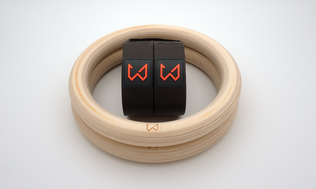 Wooden fitness rings with black straps featuring red logos on a white background