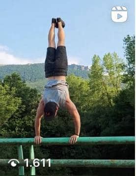 Atleta maschio che fa la verticale con uno splendido paesaggio sullo sfondo