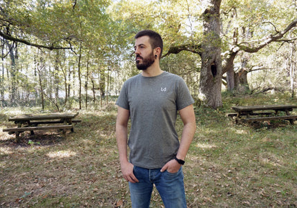 Man standing in a forested area with picnic tables wearing hemp and organic cotton tshirt.