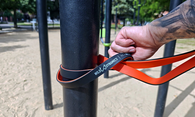 Athlete setting up resistance bands around a vertical pole in a calisthenics park