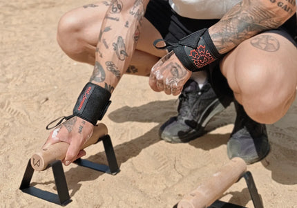 Person with tattoos holding parallettes outdoors