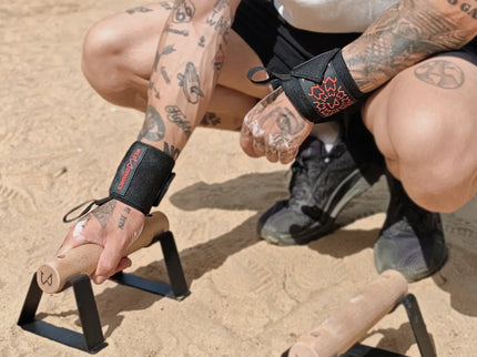 Person with tattoos holding parallettes outdoors