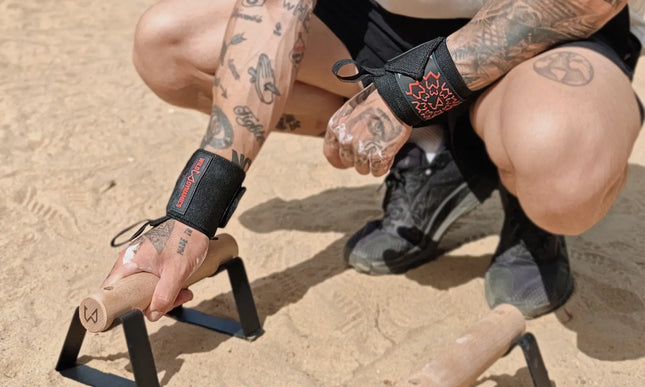 Person with tattoos holding parallettes outdoors