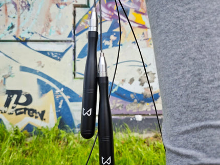 Person holding two black jump ropes with a colorful mural in the background