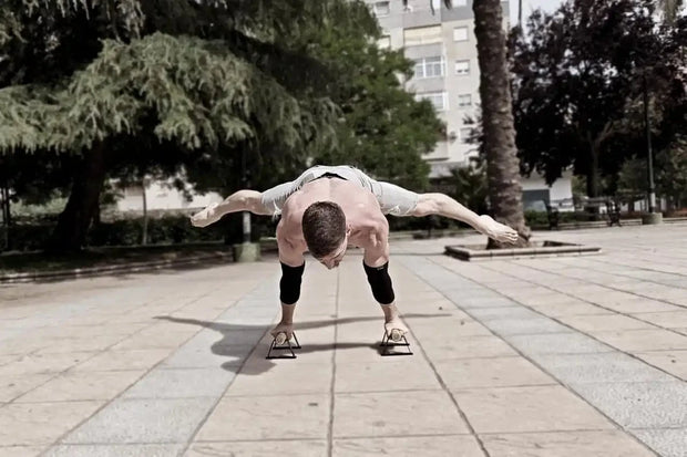 Person performing a handstand on a skateboard in an urban park setting