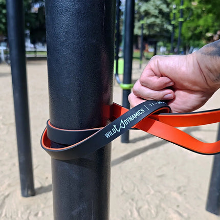 Person using wild dynamics resistance band on outdoor exercise equipment