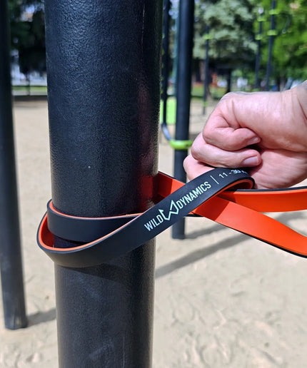 Person using wild dynamics resistance band on outdoor exercise equipment