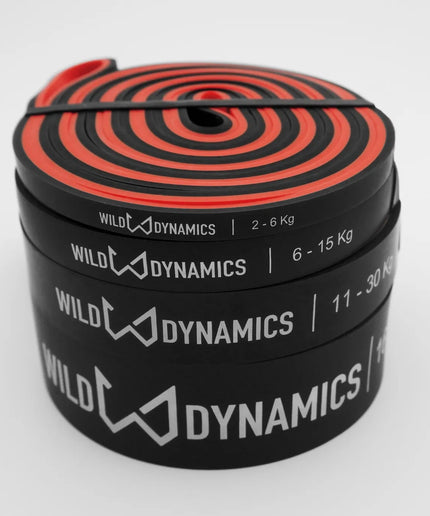 Stack of resistance bands with red and black design, labeled 'Wild Dynamics', on a white background.