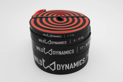 Stack of resistance bands with red and black design, labeled 'Wild Dynamics', on a white background.