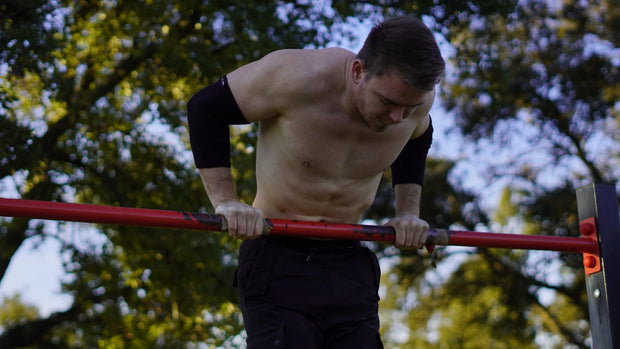 Athlete doing bar dips wearing elbow sleeves of wilddynamics