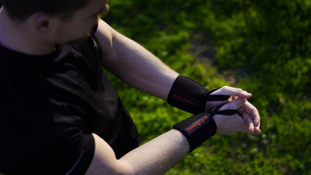 Person wearing black wrist wraps outdoors on a grassy background