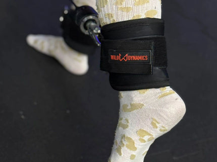 Person wearing a black ankle strap with a visible brand logo on a dark background