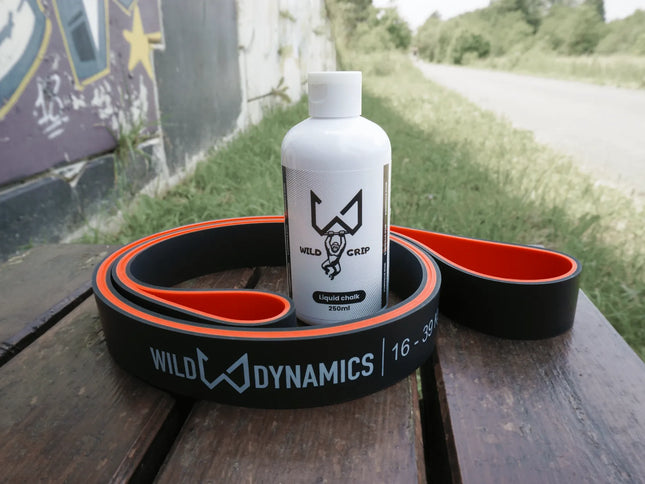 Liquid chalk bottle with 'Wild Dynamics' branding on a wooden surface outdoors.