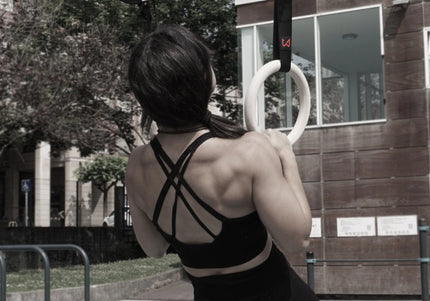 Female calisthenics athlete doing pull up on wooden rings of wild dynamics
